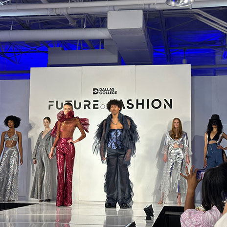 several models stand on a runway; Dallas College Future of Fashion can be seen on the backdrop